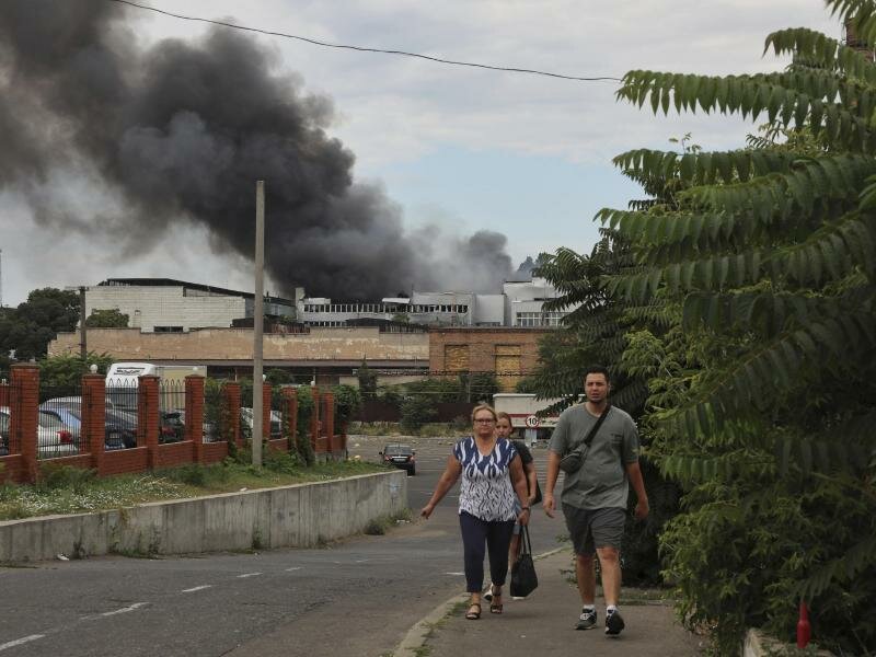 Rauch steigt nach russischem Beschuss hinter diesen Menschen in Odessa auf. Foto: Nina Lyashonok/AP/dpa