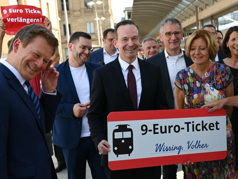 Volker Wissing mit einem «9-Euro-Ticket», das ihm im Mainzer Hauptbahnhof von einem Umweltaktivisten überreicht wurde. Foto: Arne Dedert/dpa