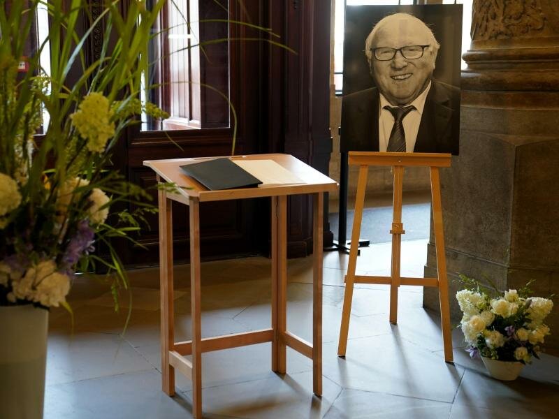 Ein Foto von Uwe Seeler steht auf einer Staffelei neben dem Kondolenzbuch im Hamburger Rathaus. Foto: Marcus Brandt/dpa