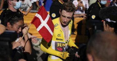 Jonas Vingegaard und seine Freundin Trine Hansen (l, mit der dänischen Fahne) sind nach dem Einzelzeitfahren emotional überwältigt. Foto: Daniel Cole/AP/dpa