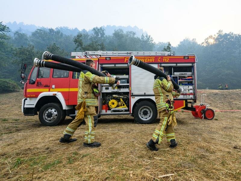 Feuerwehrleute arbeiten am Elbufer an der Löschwasserversorgung im Kampf gegen die Waldbrände im Nationalpark Sächsische Schweiz. Foto: Robert Michael/dpa