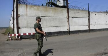 Ein Soldat steht Wache neben der Mauer eines Gefängnisses in Oleniwka. Foto: -/AP/dpa
