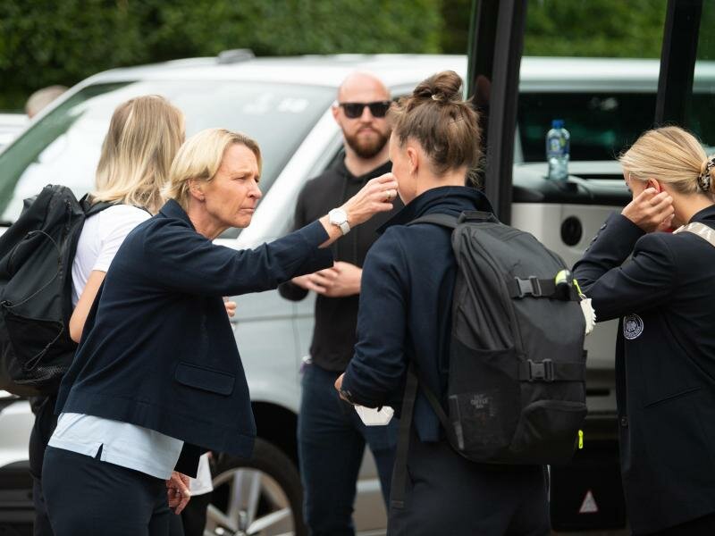 Bundestrainerin Martina Voss-Tecklenburg (l) versucht Spielerinnen bei der Abreise aufzumuntern. Foto: Sebastian Gollnow/dpa