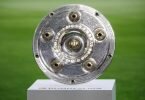 Die Meisterschale ist vor Spielbeginn auf einem Podest zu sehen. Foto: Matthias Balk/dpa