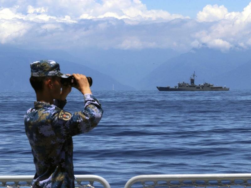 Ein Mitglied der chinesischen Volksbefreiungsarmee während einer Militärübung auf See - im Hintergrund Taiwans Fregatte Lan Yang. Foto: Lin Jian/Xinhua/AP/dpa