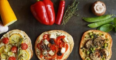 Gelbe Zucchini, rote Paprikaschoten oder grüne Erbsen - der Belag für die Mini-Pizzen erinnert an eine Ampel. Foto: Manfred Zimmer/herrgruenkocht.de/dpa-tmn