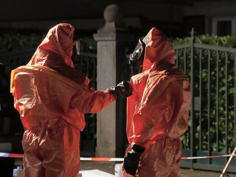 Einsatzkräfte stehen in Schutzanzügen auf der betroffenen Straße im Grunewald. Foto: Paul Zinken/dpa