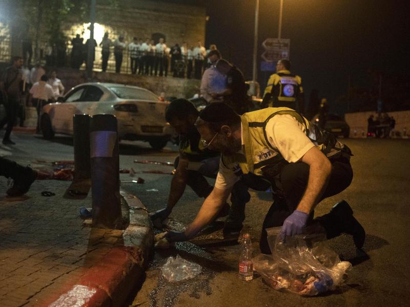 Freiwillige des Zaka-Rettungsdienstes säubern den Schauplatz mehrerer Schüsse, bei dem mehrere Israelis in der Nähe der Altstadt von Jerusalem verletzt wurden, am frühen Sonntag. Foto: Maya Alleruzzo/AP/dpa