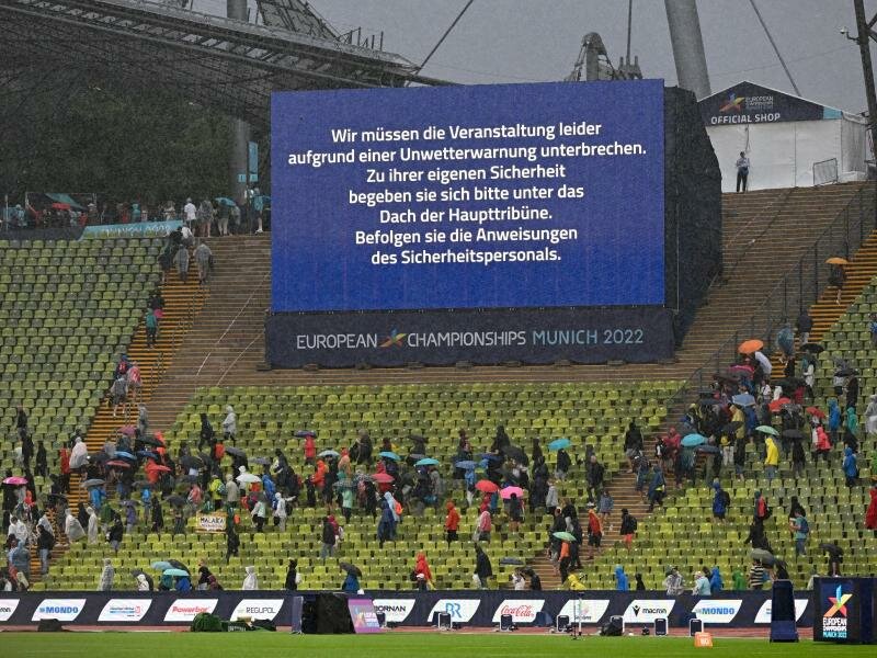 Zuschauer mit Regenschirmen verlassen die Plätze. Foto: Sven Hoppe/dpa