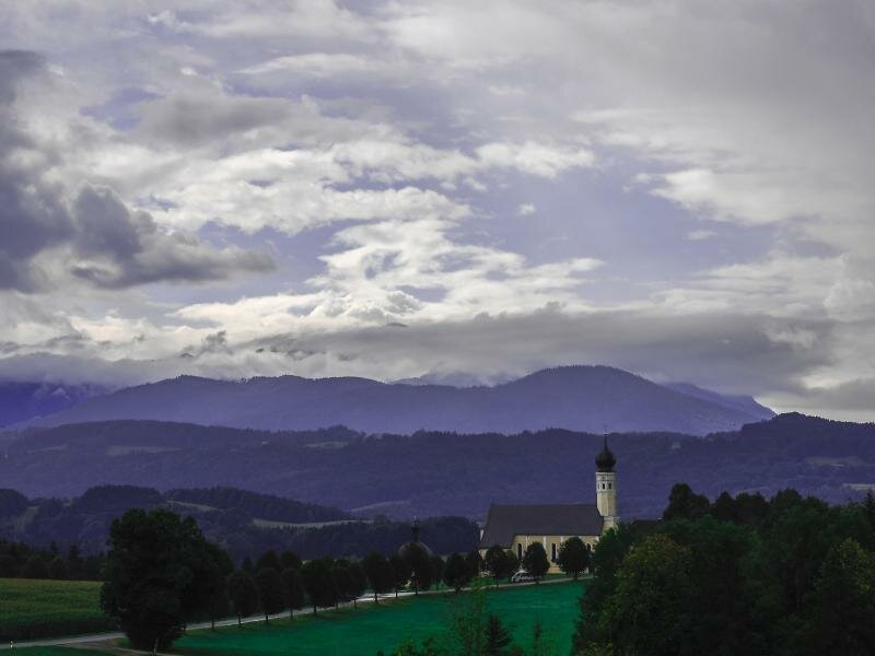 Wechselhaftes Wetter: Am Himmel über der bayerische Kirche von Wilparting in Irschenberg ziehen Wolken herüber. Foto: Uwe Lein/dpa