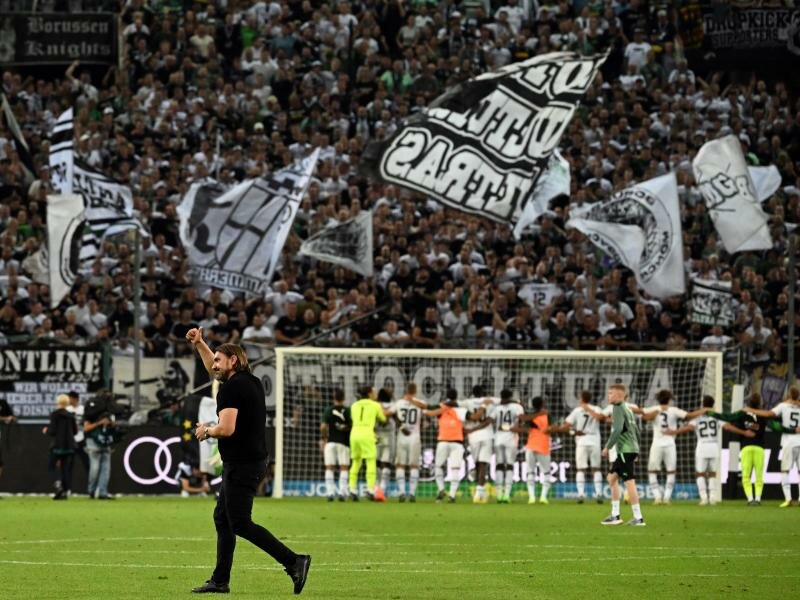 Die Gladbach-Fans feiern die Mannschaft - Trainer Daniel Farke (vorne) feiert im Stillen mit. Foto: Federico Gambarini/dpa