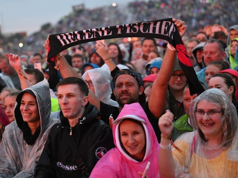 Eine Rekordzahl von 130.000 Fans feierte mit Regenponchos im strömenden Regen. Foto: Angelika Warmuth/dpa