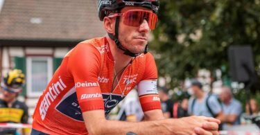 Der Brite Adam Yates im roten Trikot des Gesamtführenden am Start der 4. und damit letzten Etappe. Foto: Philipp von Ditfurth/dpa