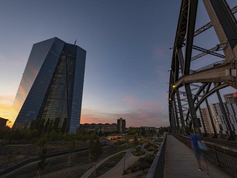 Das Licht der untergehenden Sonne spiegelt sich in der EZB-Glasfassade in Frankfurt am Main. Foto: Boris Roessler/dpa