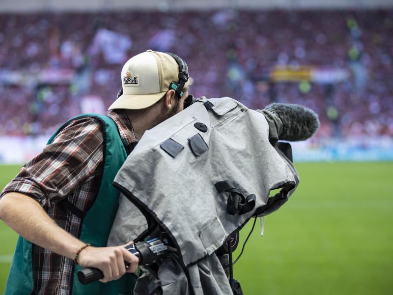 Ein Kameramann steht am Spielfeldrand und filmt ein Fußballspiel. Foto: Tom Weller/dpa