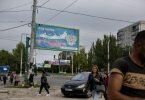Menschen gehen in der von Russland unterstützten und von Separatisten kontrollierten Volksrepublik Luhansk in der Ostukraine an einem Plakat mit der Aufschrift «Unsere Wahl - Russland» vorbei. Foto: Uncredited/AP/dpa