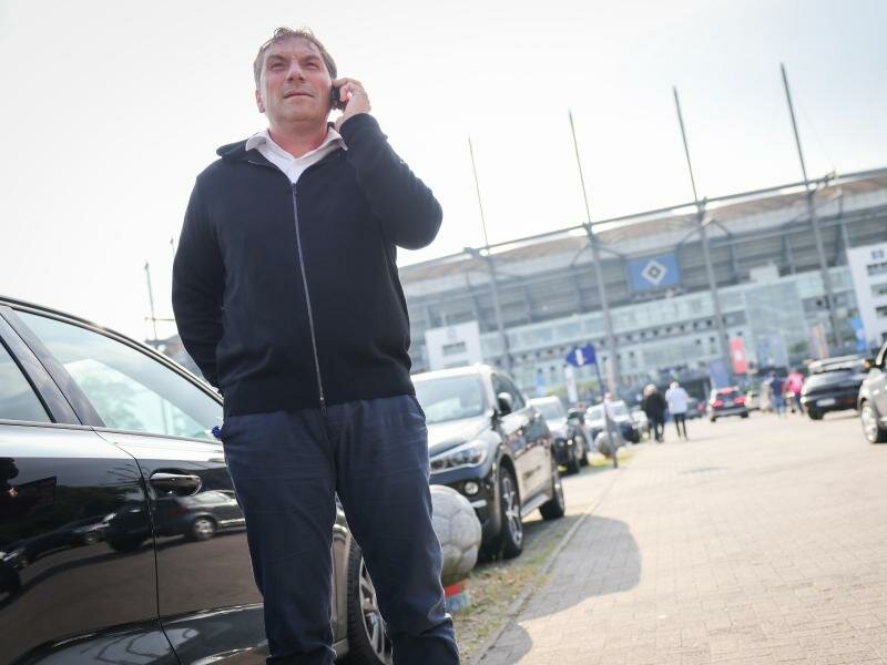 Thomas Wüstefeld, Noch-Vorstand des Hamburger SV, telefoniert vor einem Spiel auf dem Parkplatz vor dem Stadion. Foto: Christian Charisius/dpa